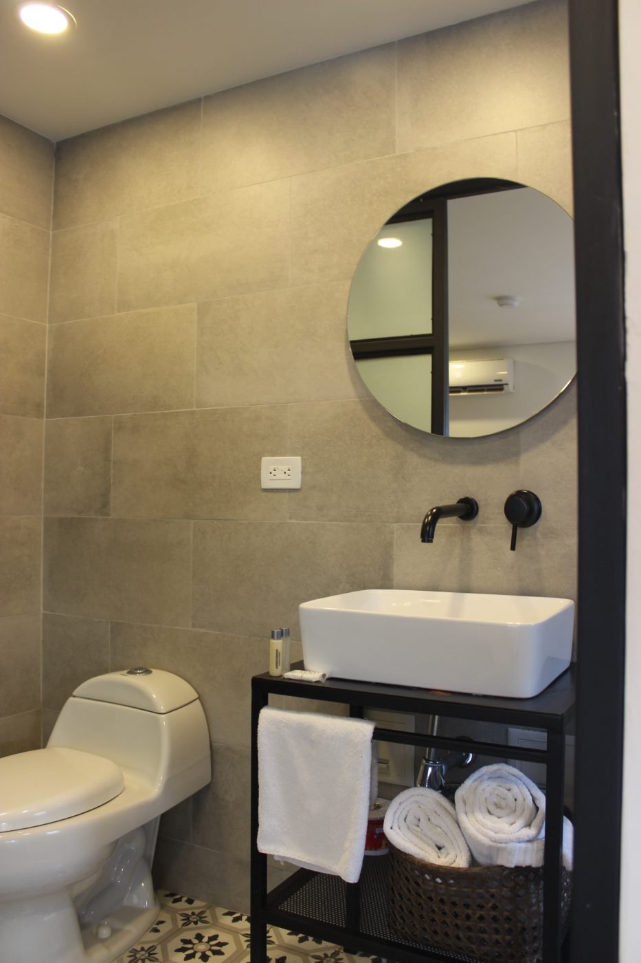 Baño de la Habitación Deluxe con lavamanos de sobreponer, espejo redondo y piso estampado