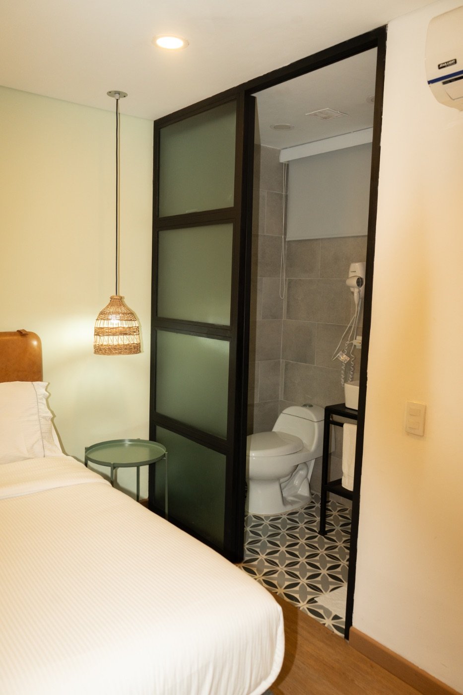 XS Room bathroom with patterned tile floor behind a frosted glass door