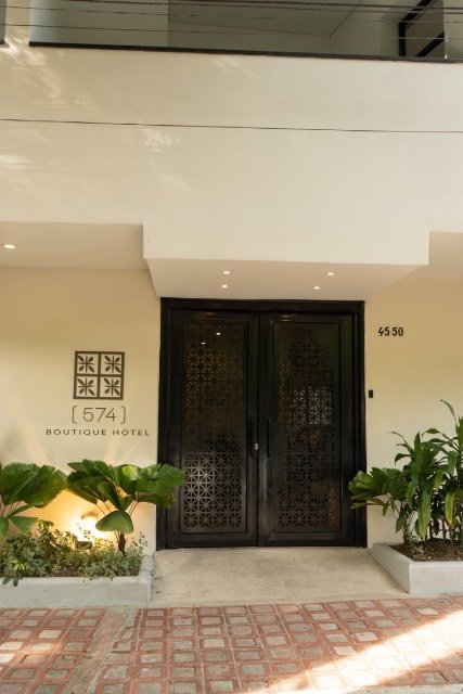 Entrance of 574 Boutique Hotel framed by tropical plants at sunset