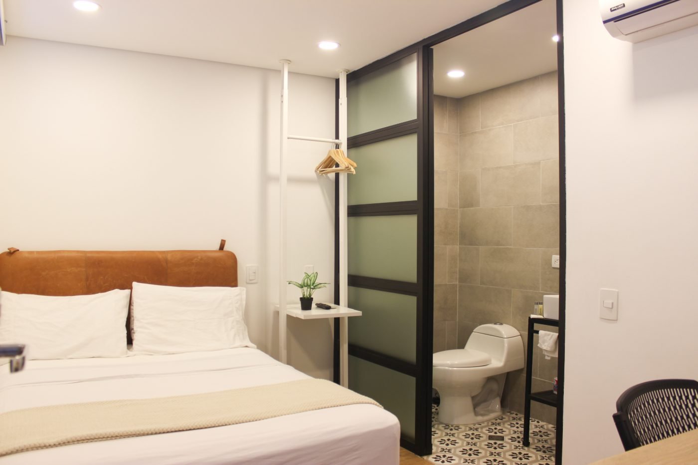 Habitación Sencilla con cabecero de cuero y división de baño en vidrio esmerilado